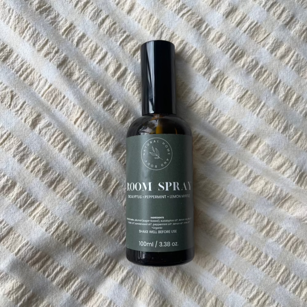 Glass room spray bottle on a bed spread.