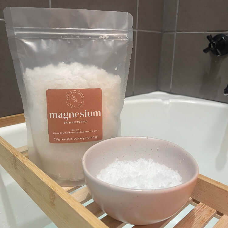 Magnesium. bath salts displayed on a bamboo bath rack across a bath tub, with another bowl beside it with some salts on display.