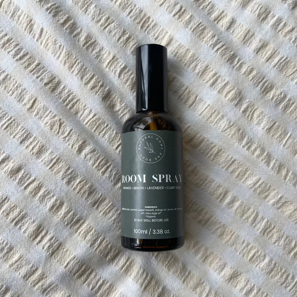 Glass room spray bottle on a bed spread.
