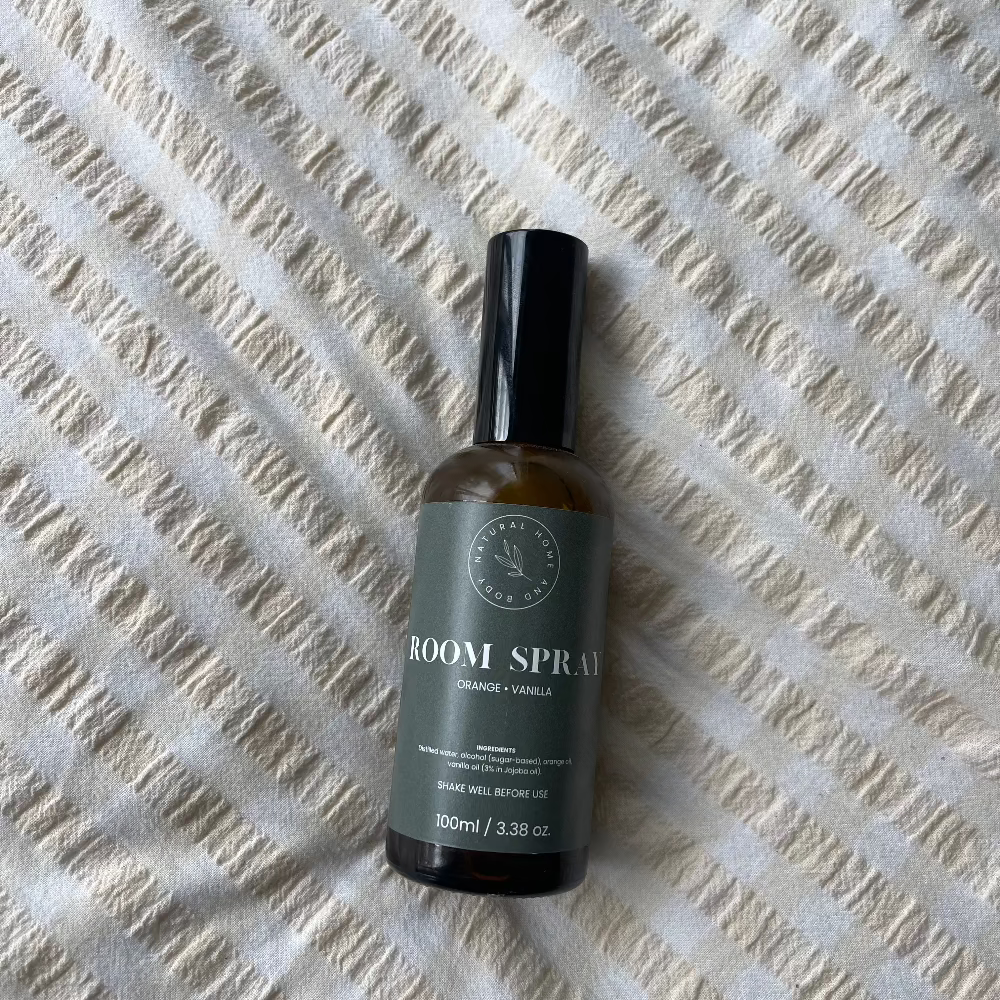 Glass room spray bottle on a bed spread.