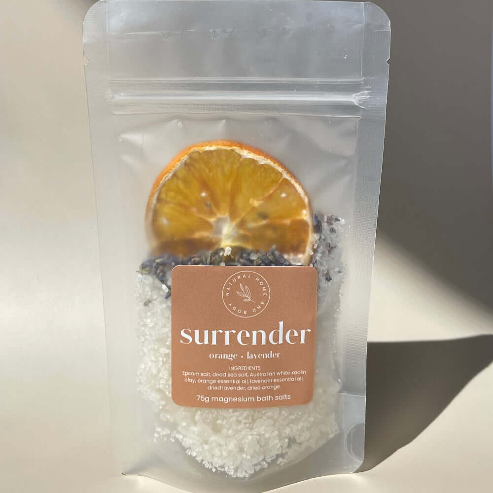 75g 'surrender' magnesium bath salts on display on a coloured background with the sun as natural lighting.