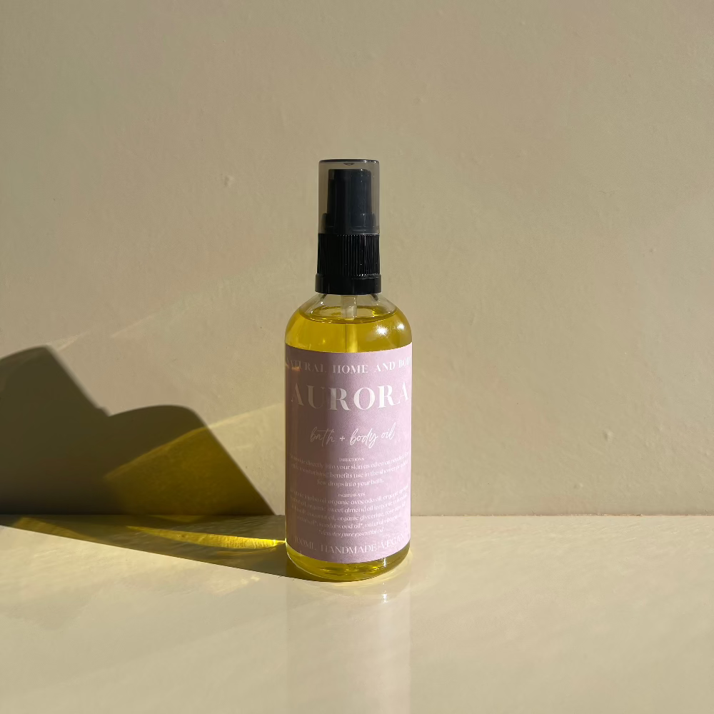 Aurora Bath & Body oil standing upright on a beige background.