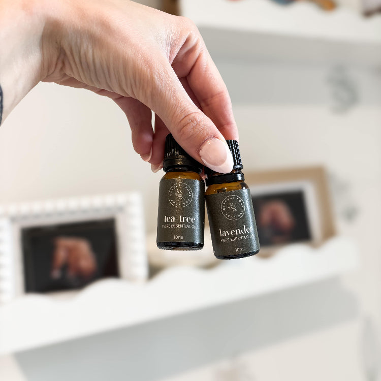 Hand holding two essential oil bottles with a blurred background.