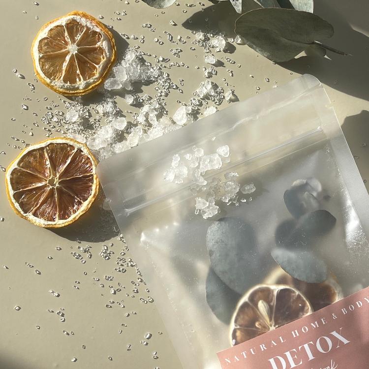 Detox magnesium bath salts laying flat on a beige background with some product surrounding it.