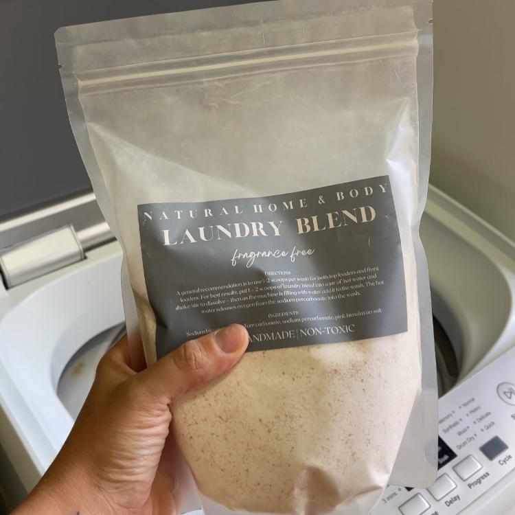 Holding a bag of our Natural Laundry Blend with a washing machine in the background.